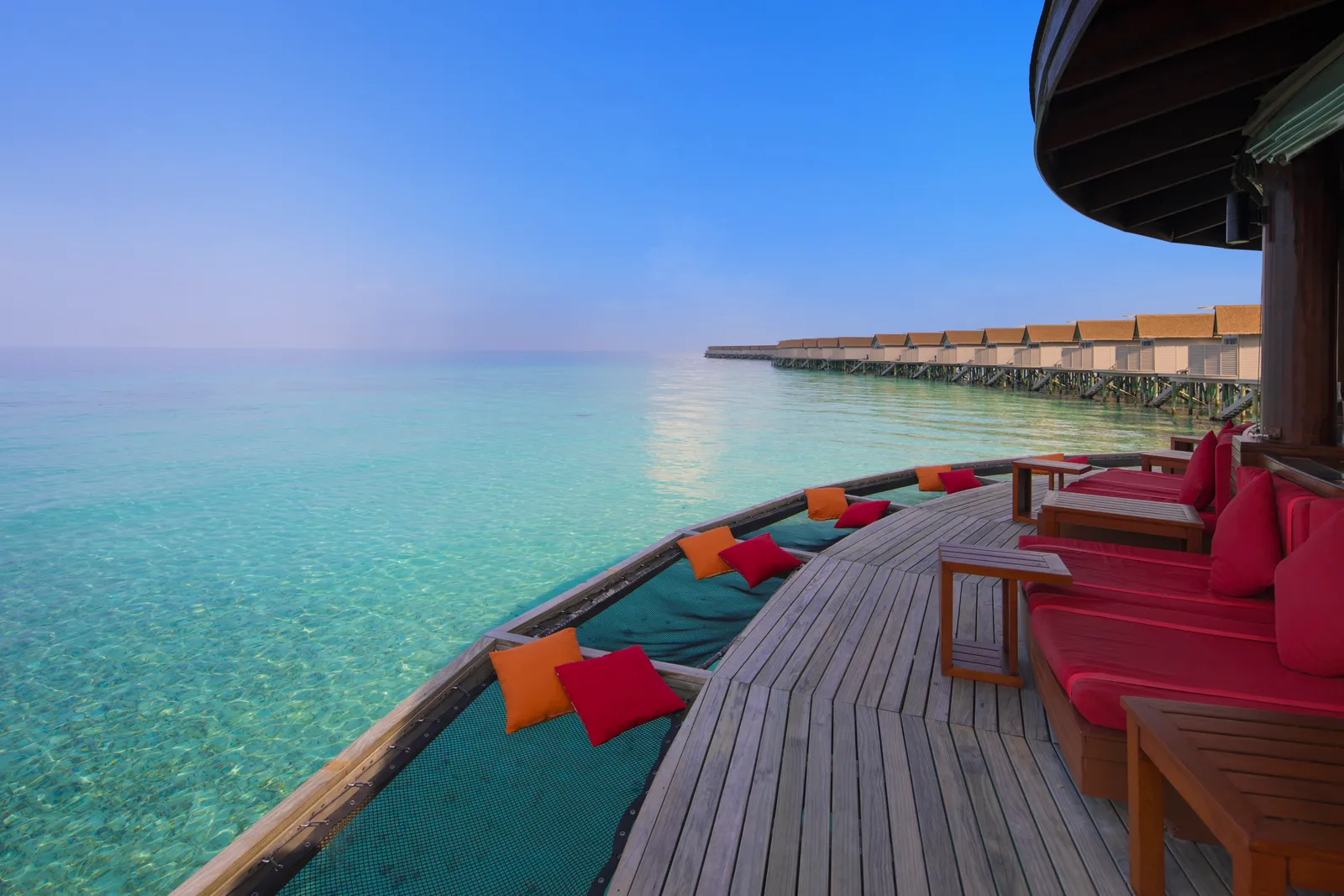 Viu Bar’s deck over the lagoon, with bright cushions and the row of water villas on the horizon.