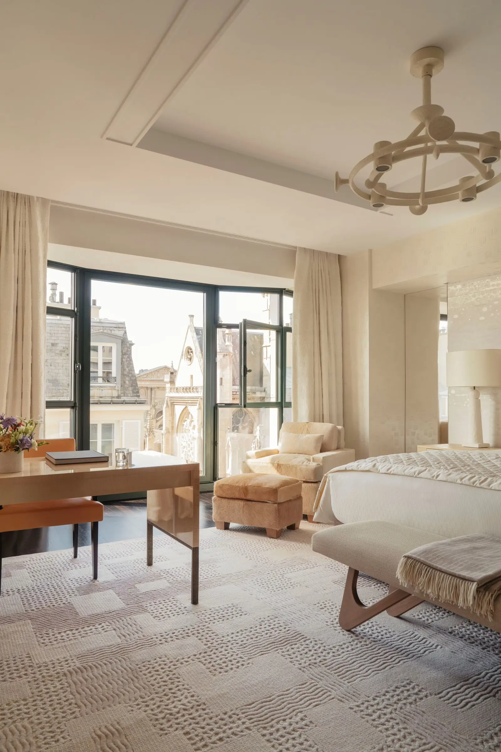 A pale bedroom with a bed, desk and sofa