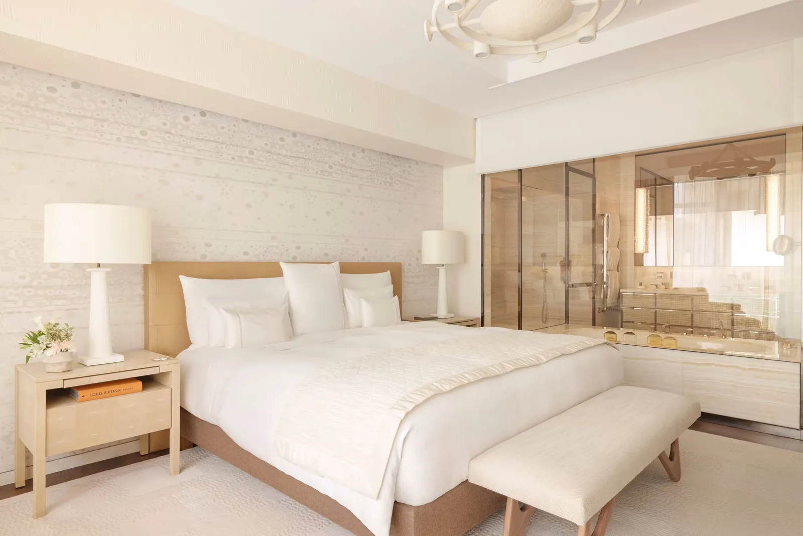 A pale bedroom with a bed and mirrored wardrobe