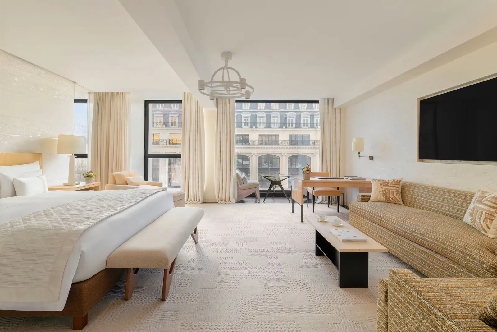 A bedroom with a bed, sofa and windows overlooking buildings