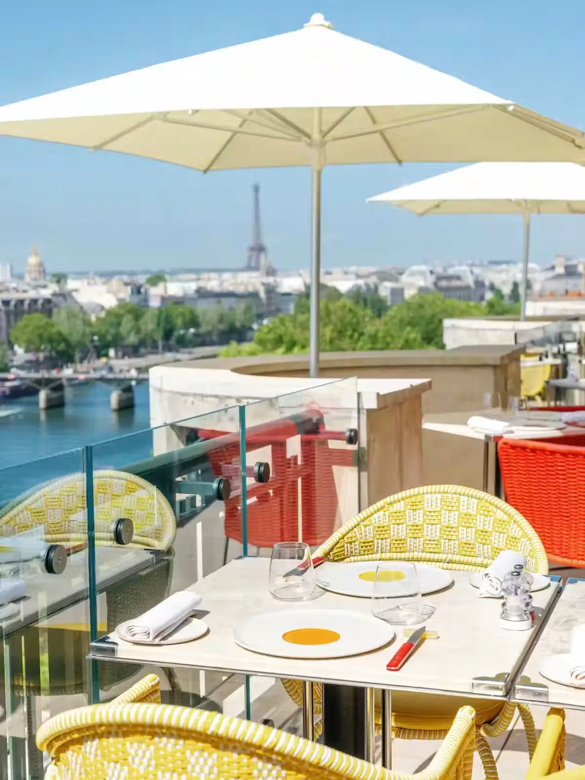 A terrace with yellow tables and chairs, parasols and city rooftops
