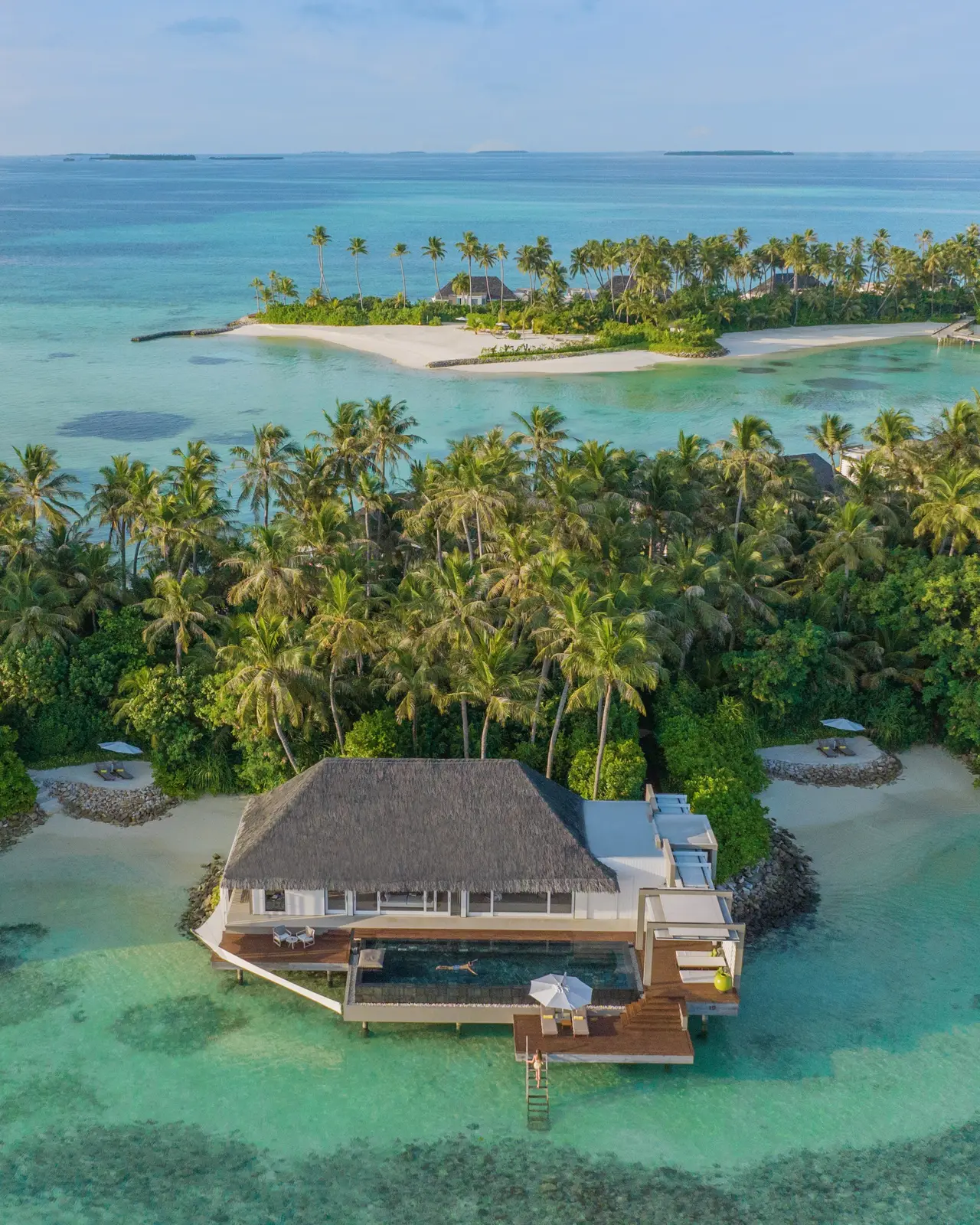 A villa among the palms from the air, turquoise lagoon around it