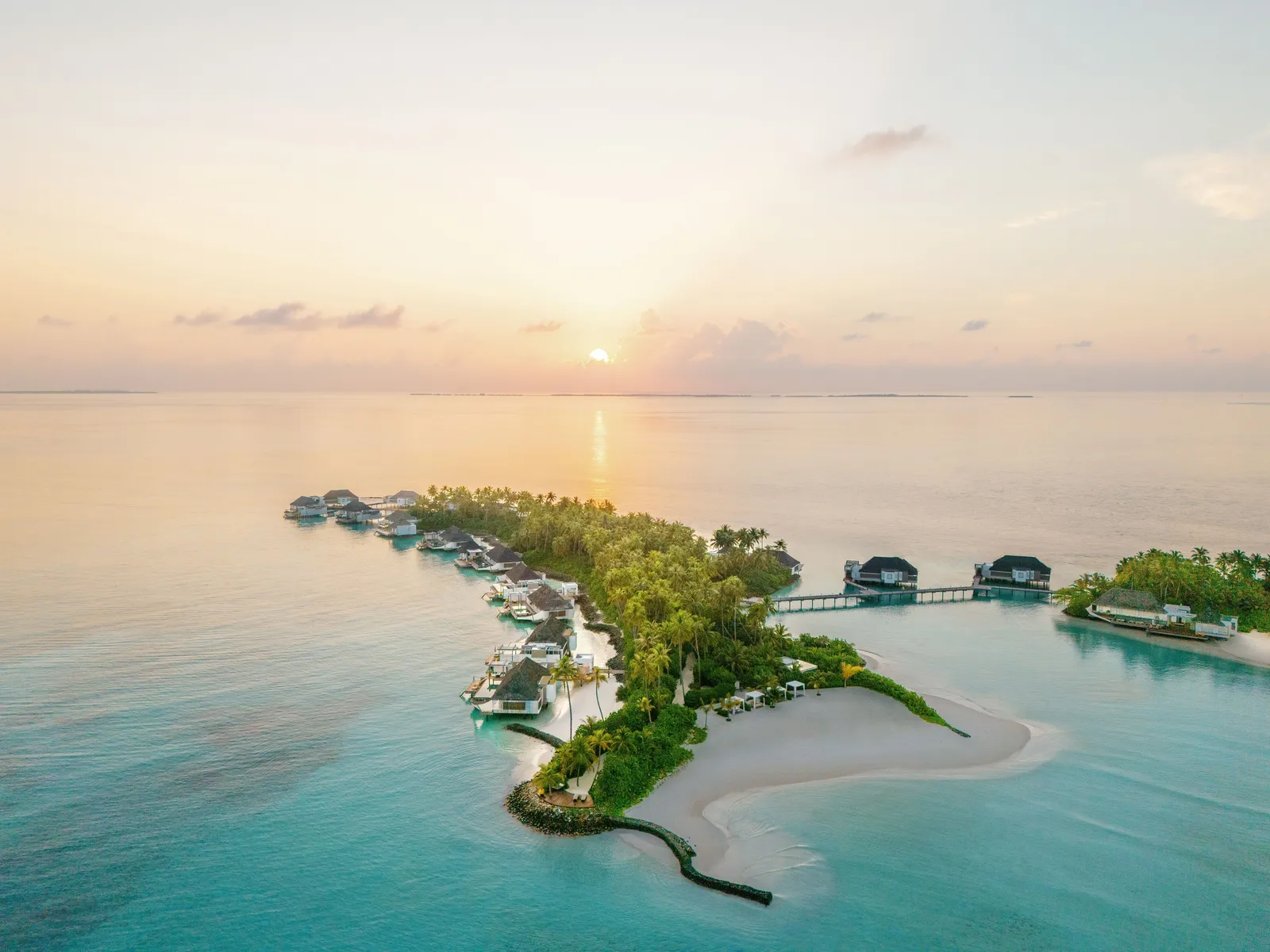 Randheli from the air at sunset: the island, its sandspit and the water villas offshore
