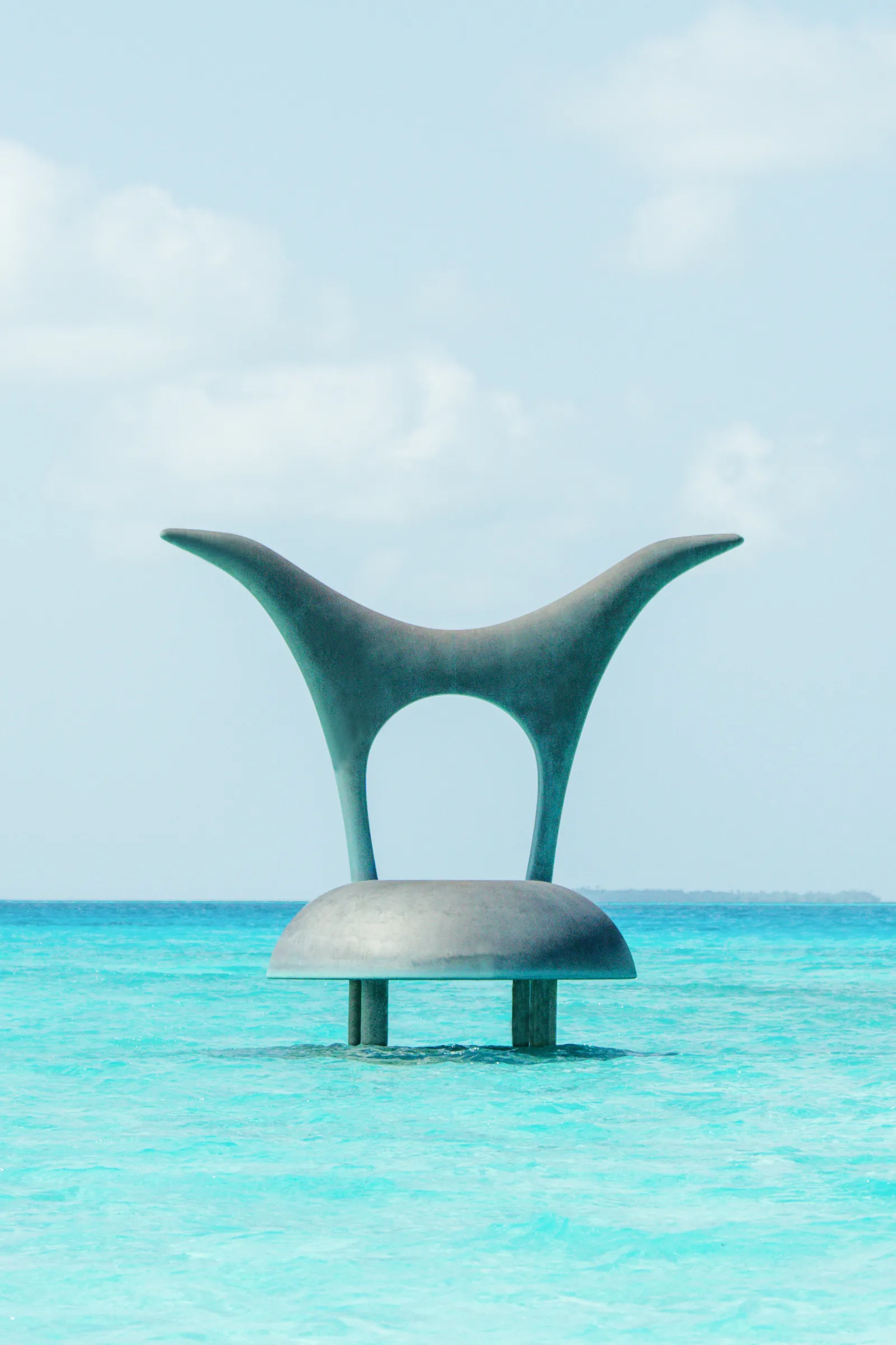 The sculpture in the lagoon, a white 2-armed form in the shallows
