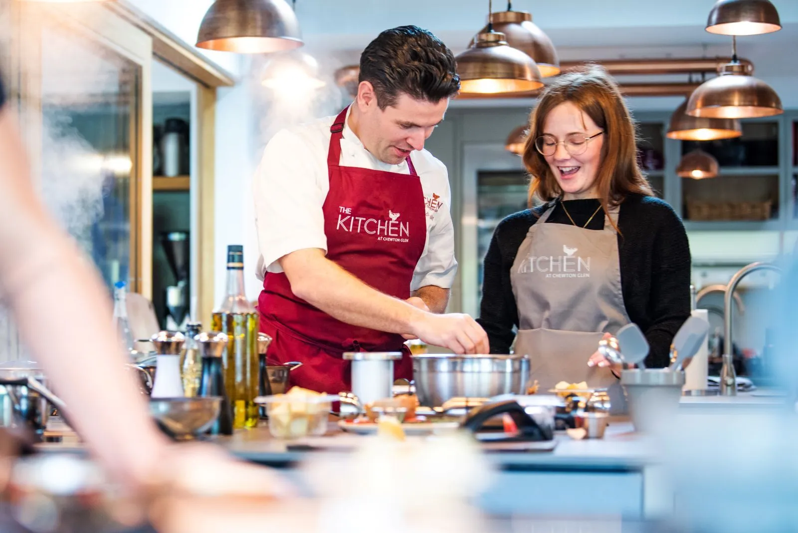 A chef and a guest at the stove during a cookery school class
