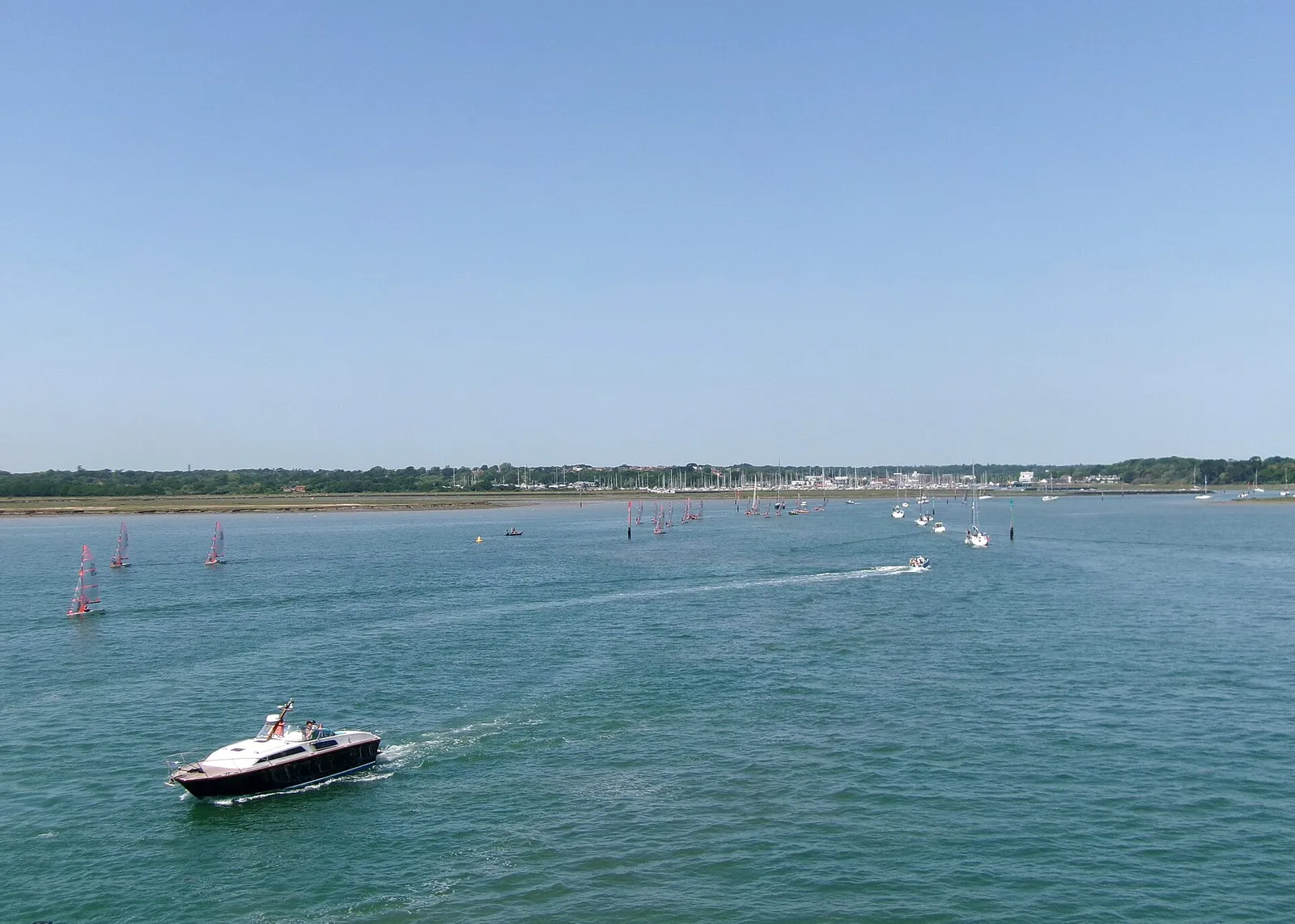 Sailing dinghies and a motor launch at the mouth of Lymington harbour