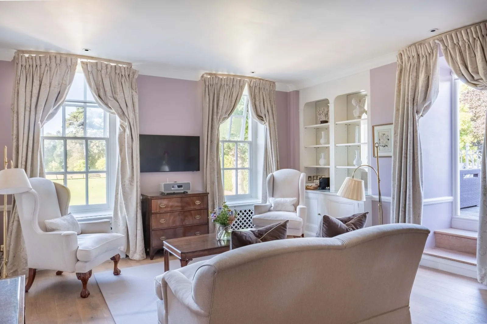 A Master Suite’s bright sitting room, armchairs and tall windows