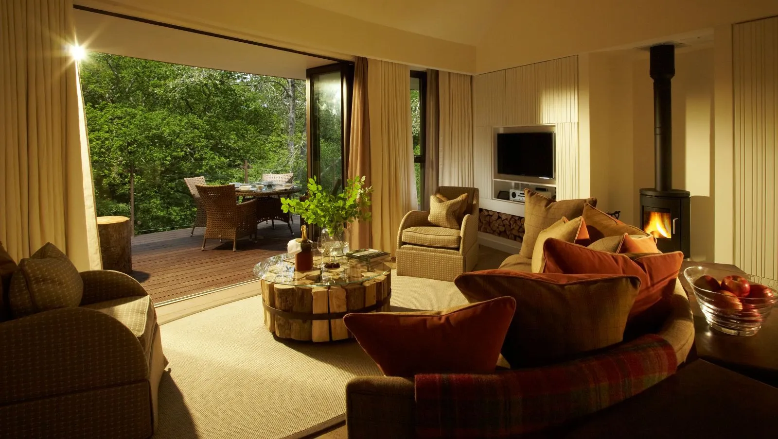 A Loft Suite’s living room, wood burner and the terrace over the woods