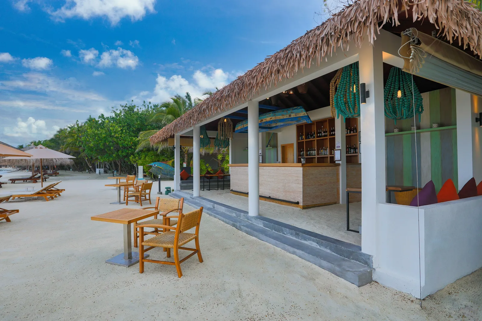 The Beach Bar beneath its thatched roof, with a table on the sand