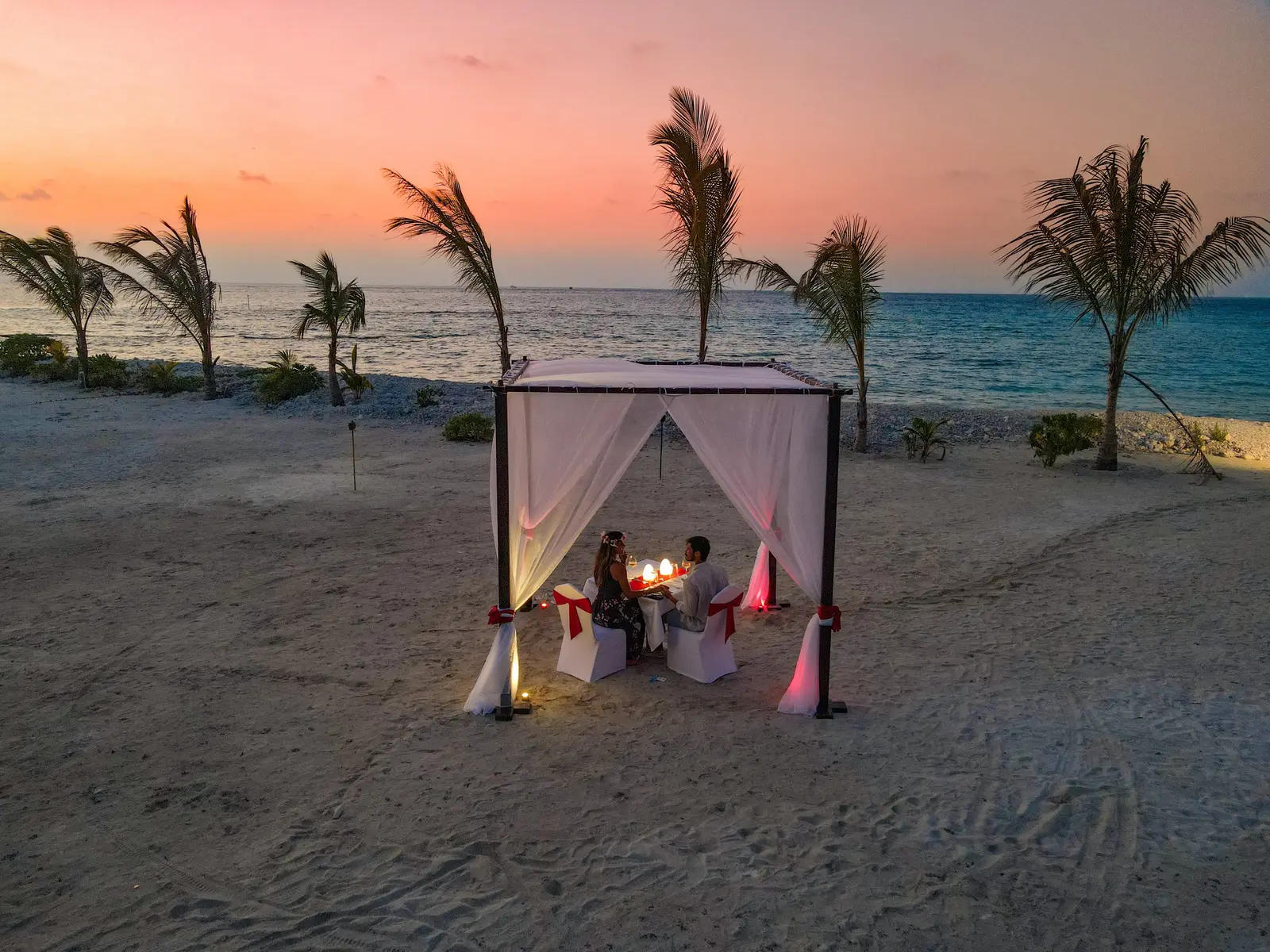 A table for 2 on the beach at sunset, under a canopy