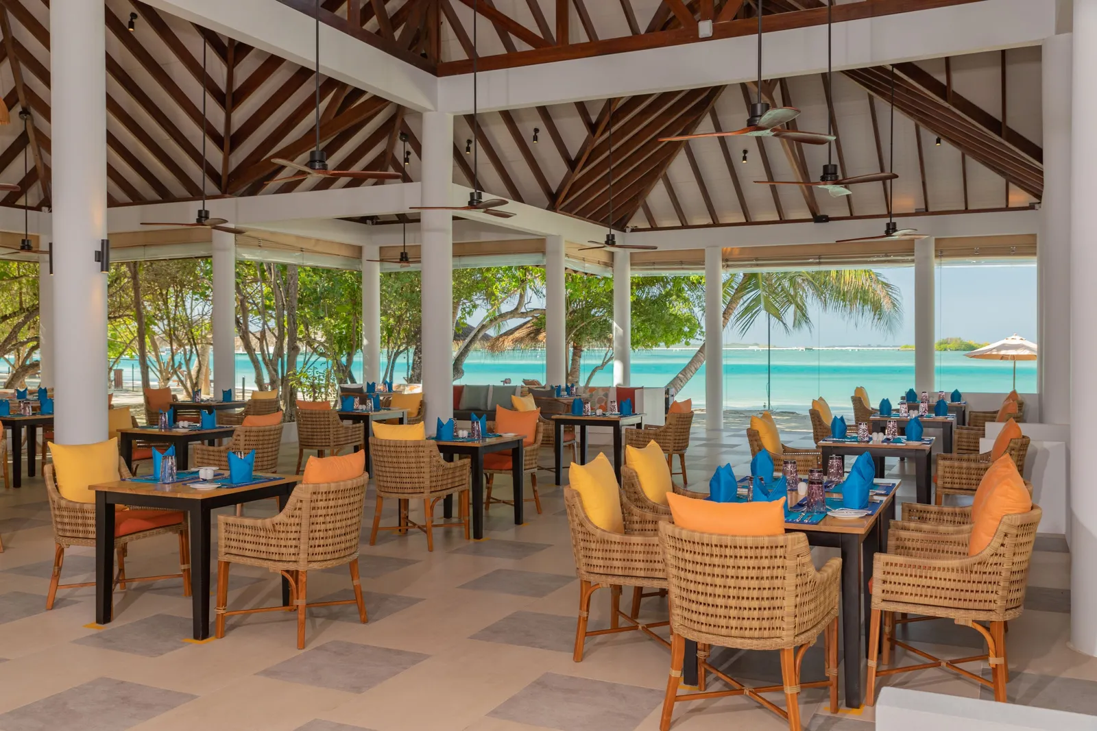 Koimala’s dining room with wicker tables beneath timber beams