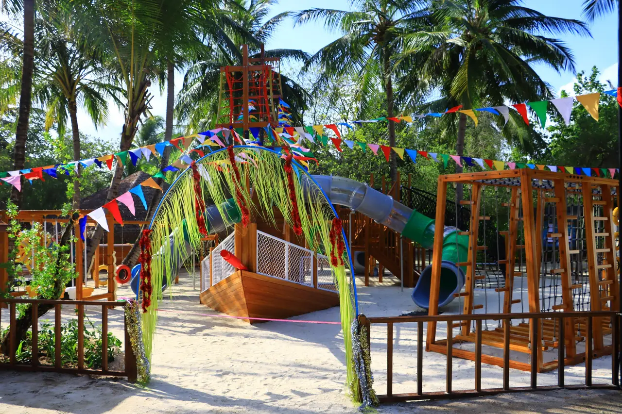 The playground on the sand with swings among the palms