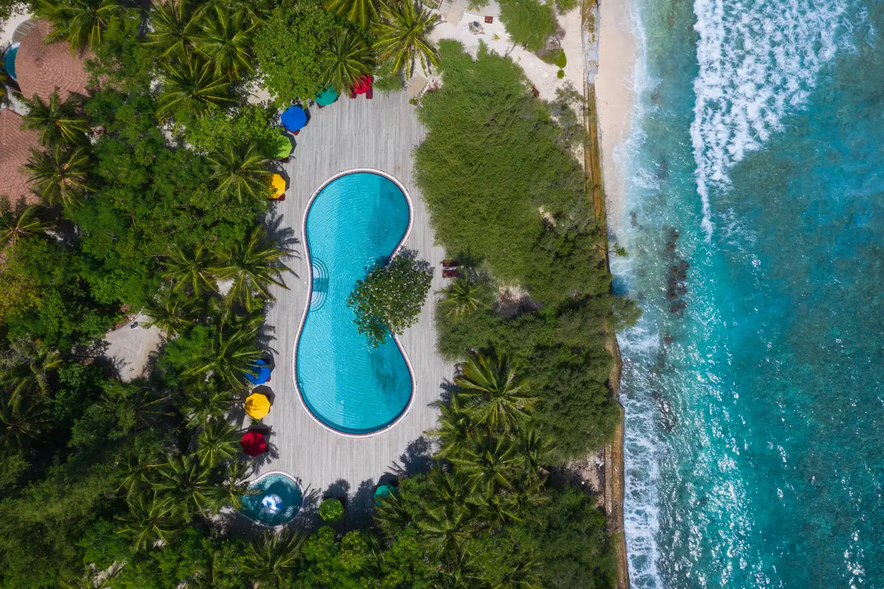The pool seen from above between the lawn, beach and sea