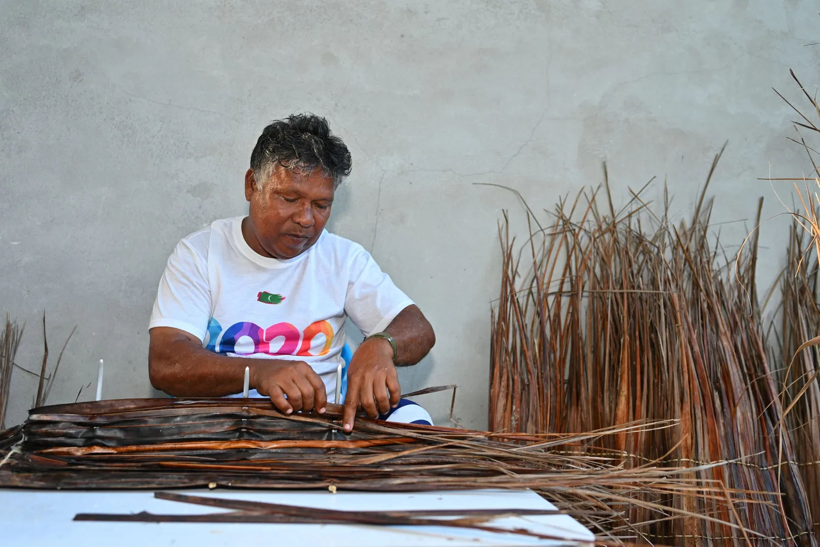 A Naalaafushi craftsman working palm fibres at a table