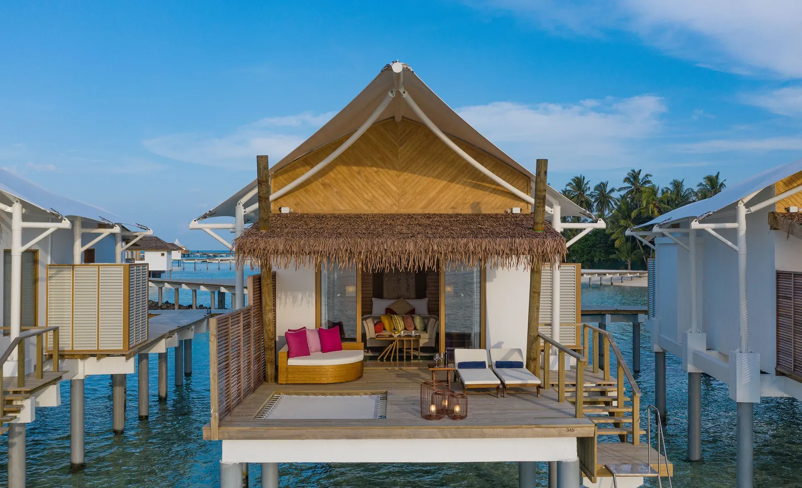 A Water Bungalow deck: the round daybed, 2 loungers and the net set into the floor above the lagoon