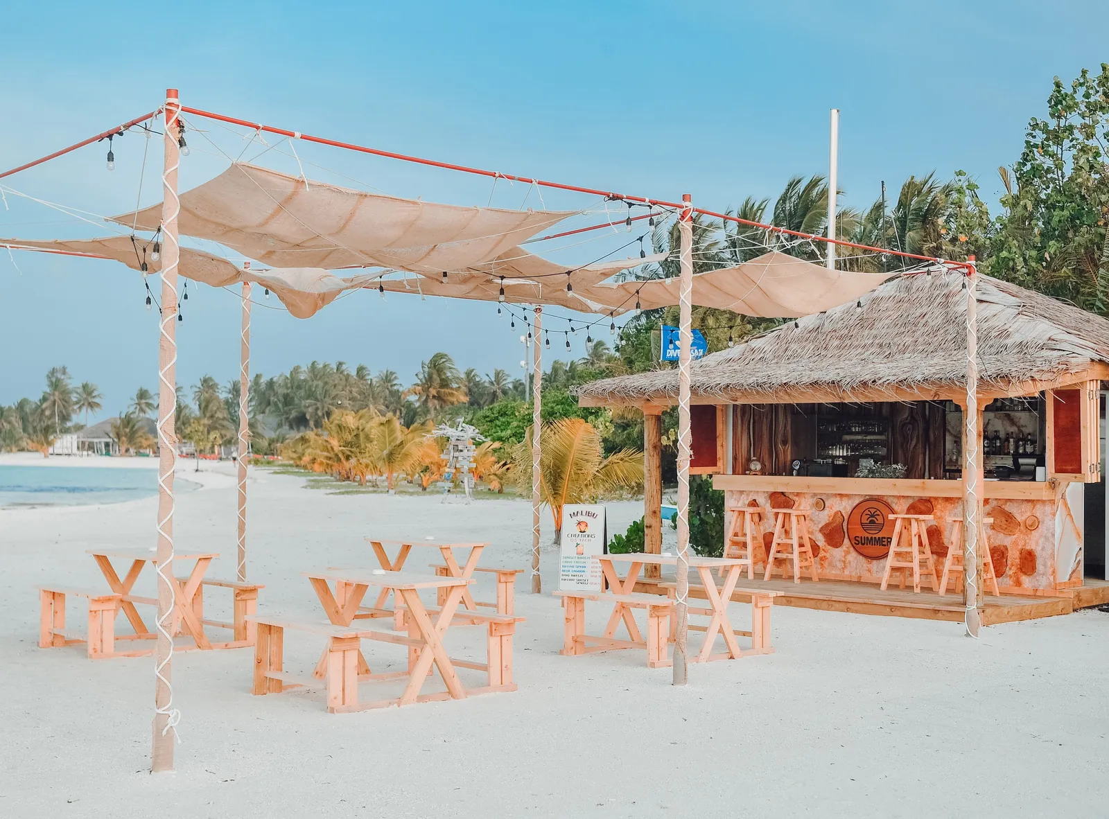 Summer Restaurant & Bar on the beach: wooden tables under sail shades and a thatched bar
