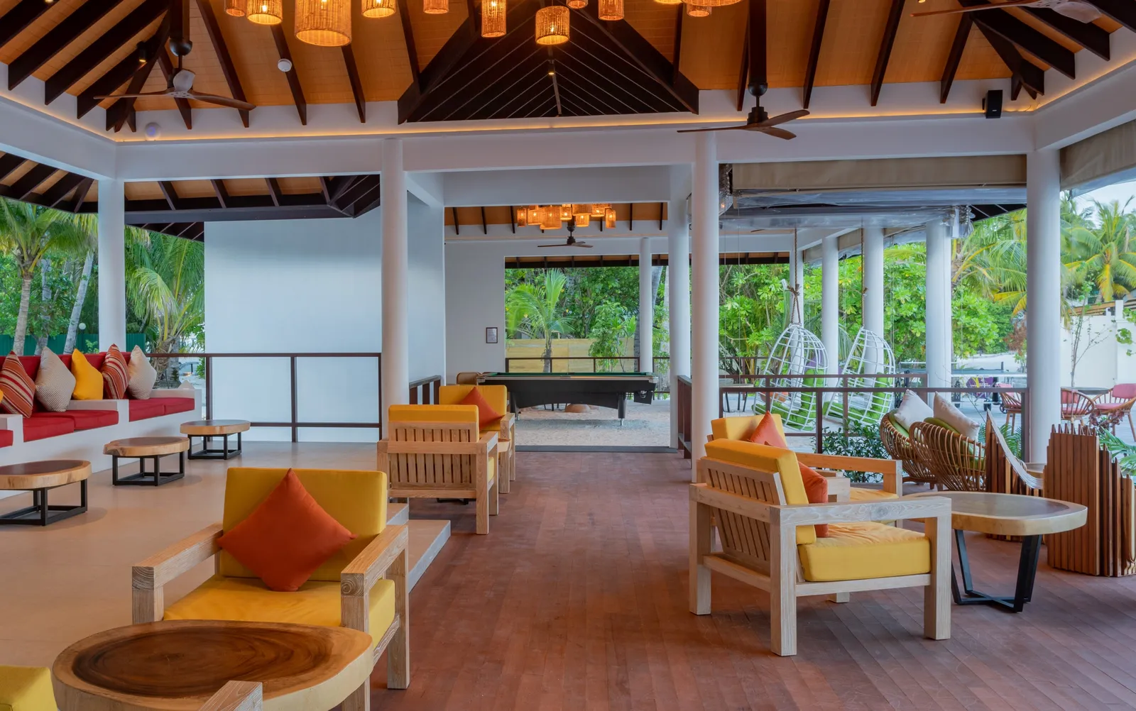 The Veli Bar by day: yellow armchairs, bright cushions and the pool table at the back