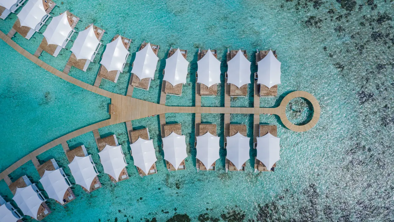 The white roofs of the water bungalows seen from above, on either side of the walkway