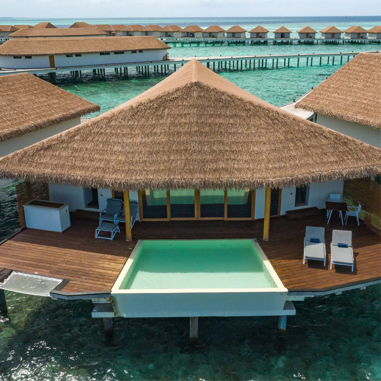 The Water Suite’s pool and deck, with overwater villas behind