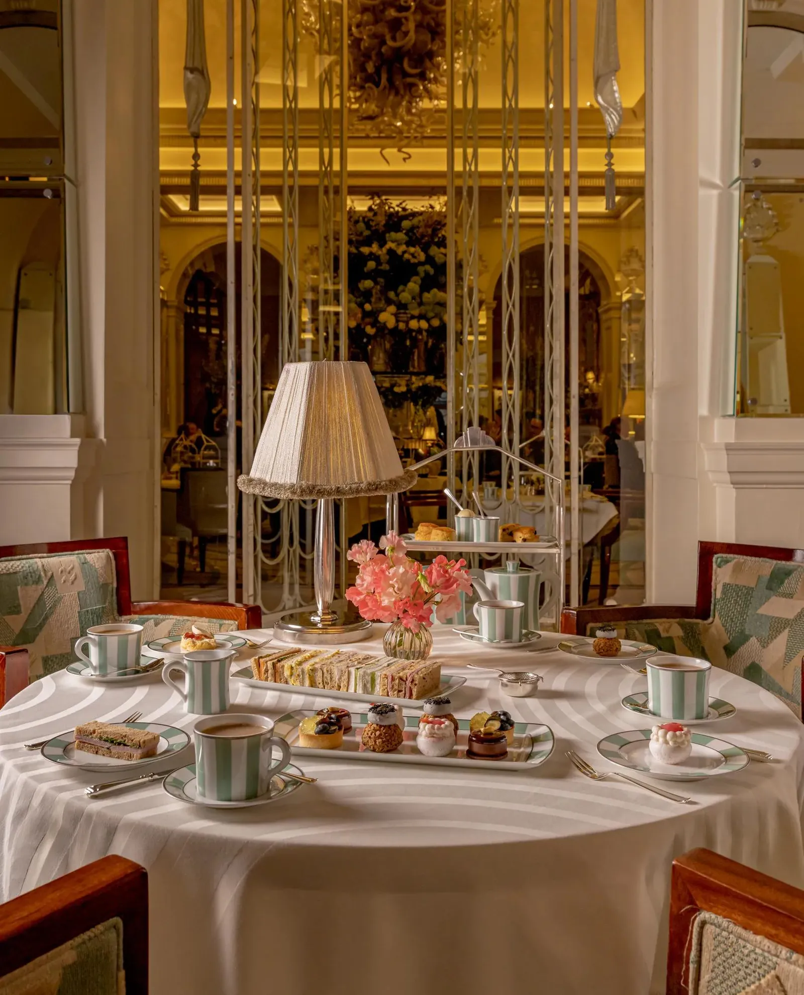 Tea in the Foyer: stands of cakes and sandwiches, green and white striped china, flowers and gilt mirrors