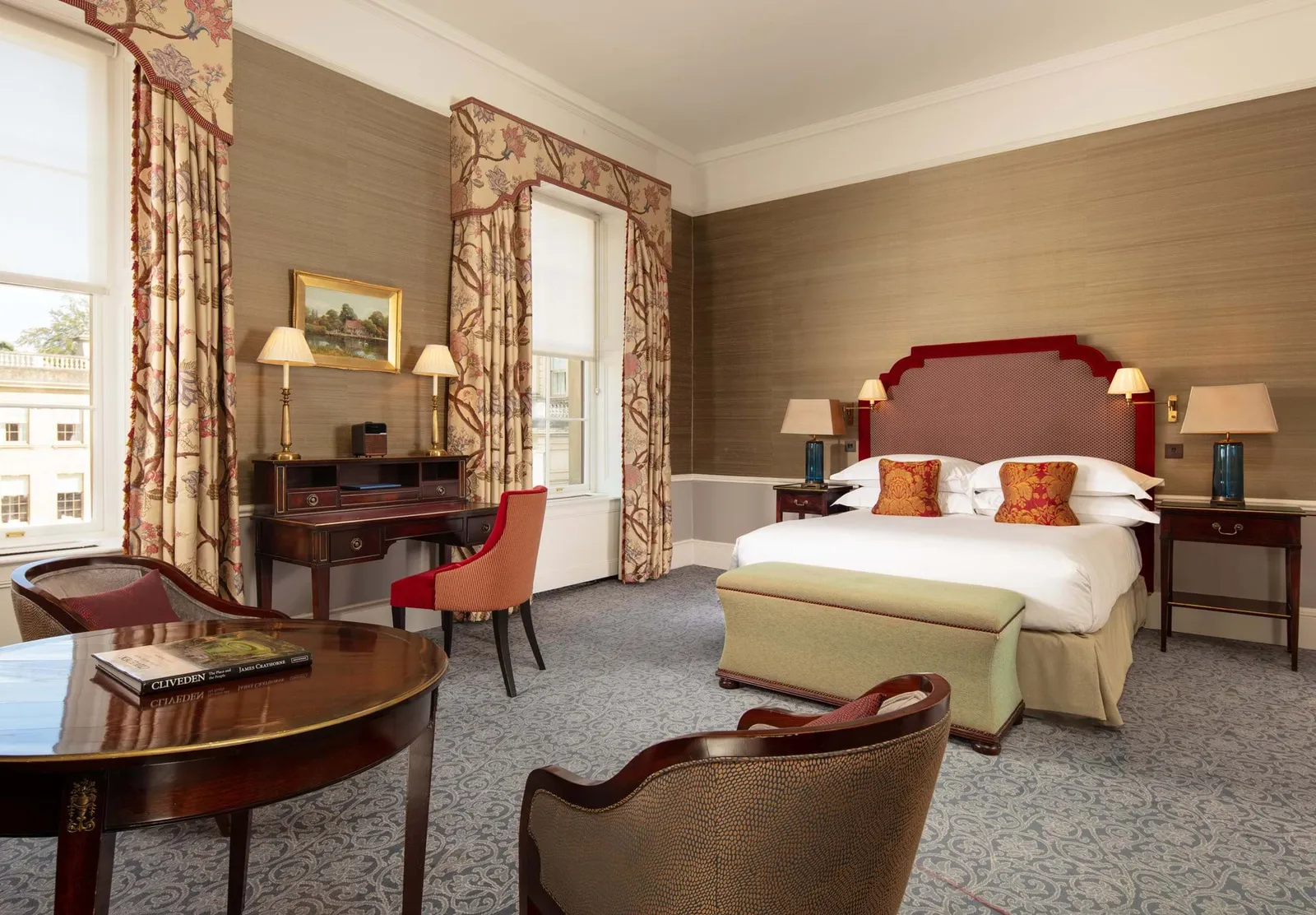 A Classic Room: a bed with a red headboard, a writing desk and patterned curtains