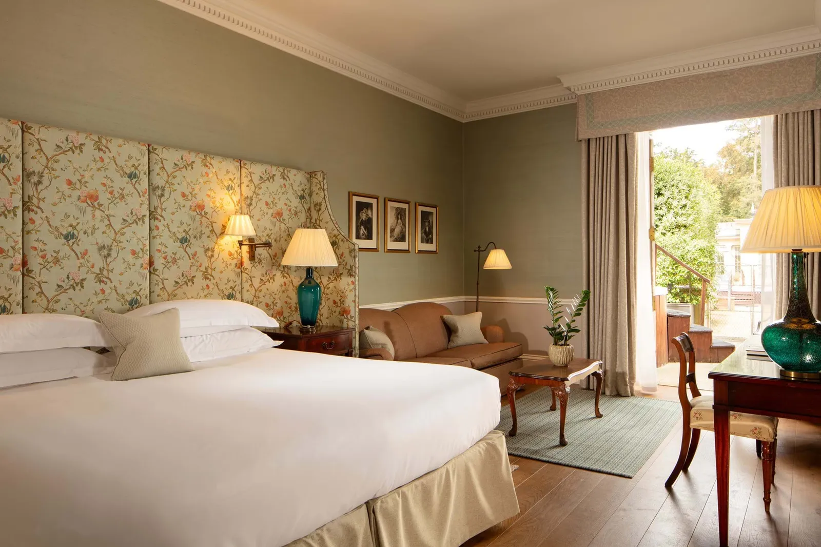 A Deluxe Double Room with a hot tub: a king bed against a painted floral panel and an open French window
