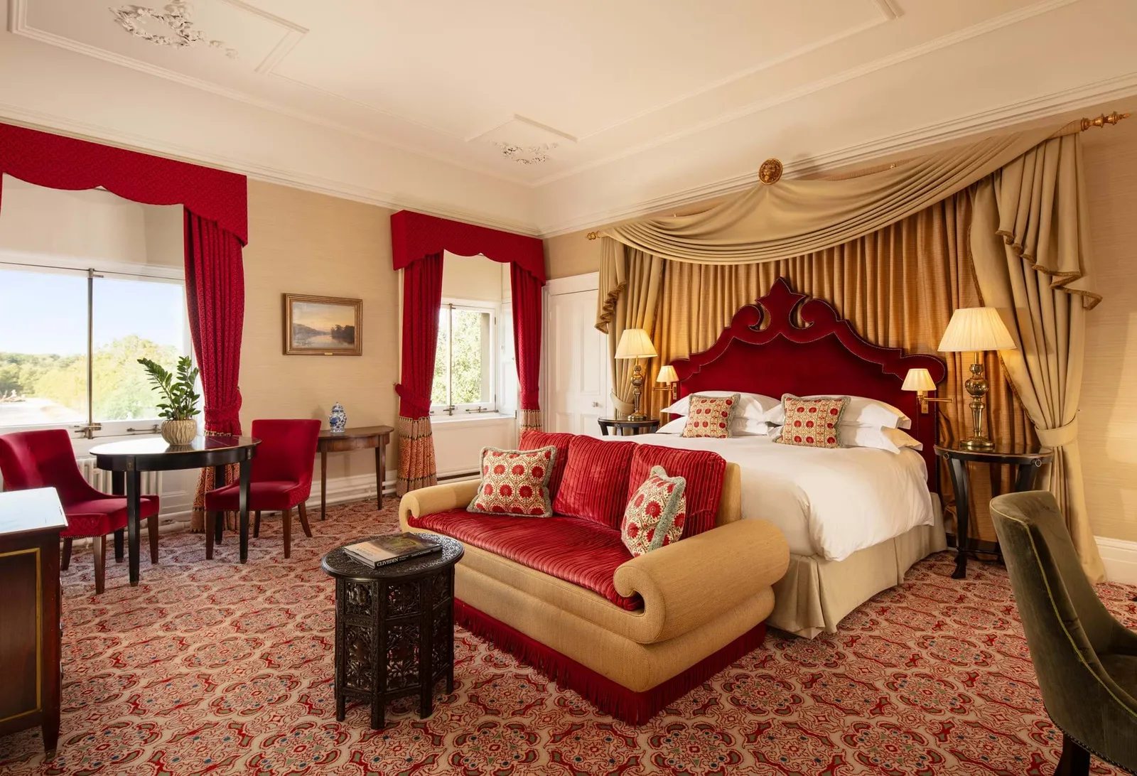 A Mansion House Deluxe Double: a red-headboard bed, a velvet sofa and crimson curtains