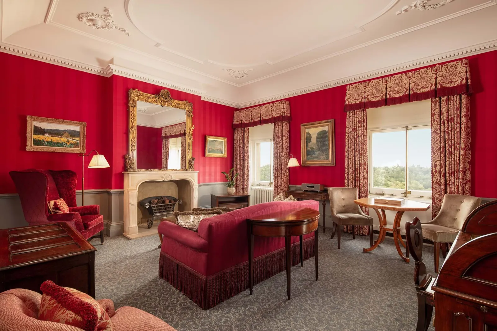 The Prince of Wales Suite: red walls, a stone fireplace with a gilt mirror and a velvet sofa