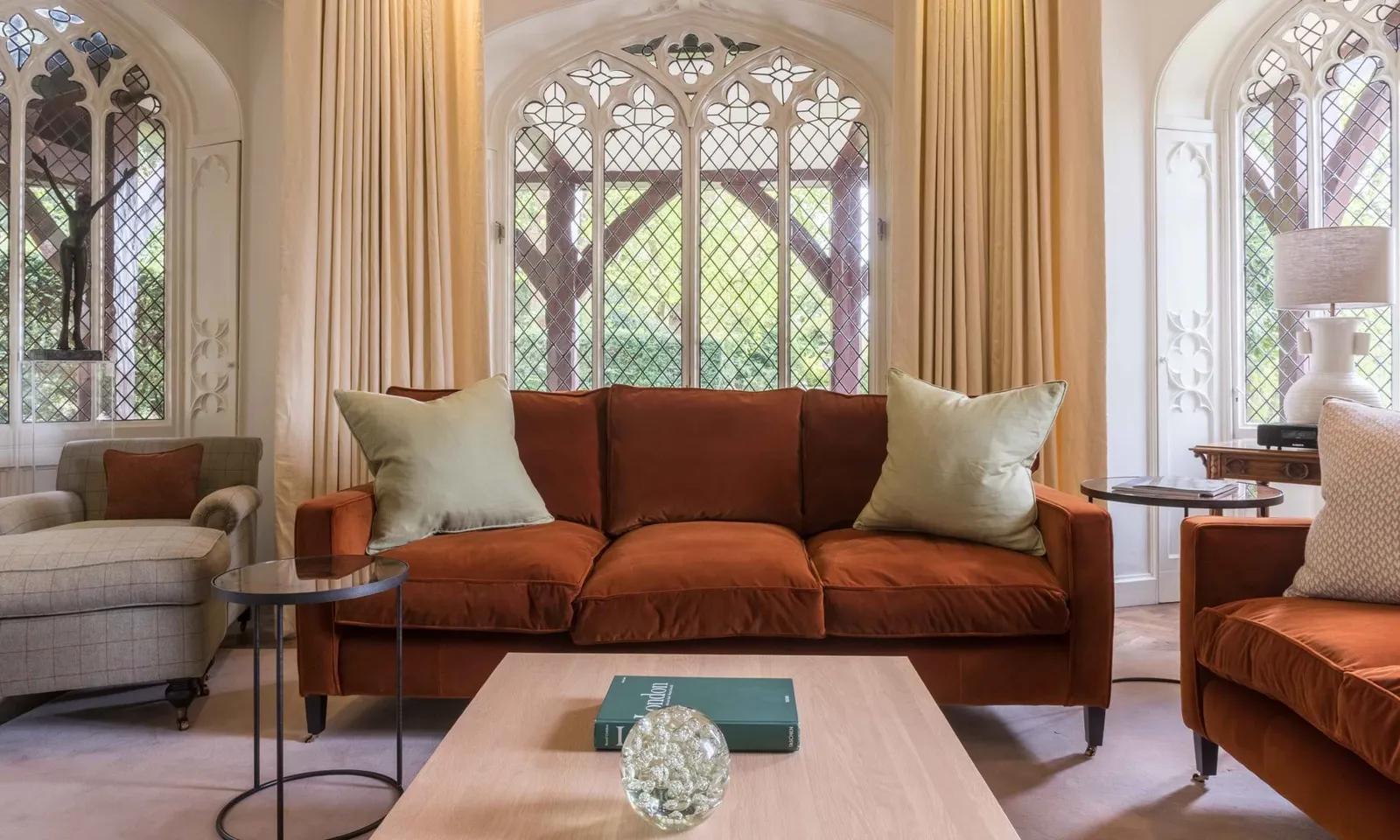 Spring Cottage’s sitting room: a rust sofa and leaded Gothic windows