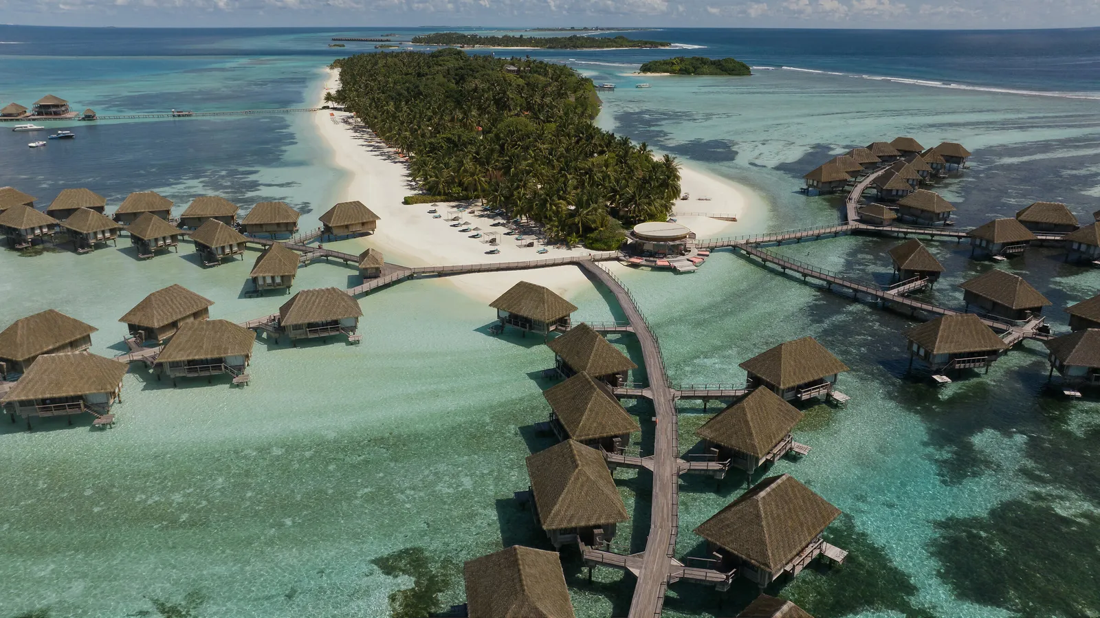 Kanifinolhu from above: the tongue of white sand, the island’s green and the 2 jetties of overwater suites.