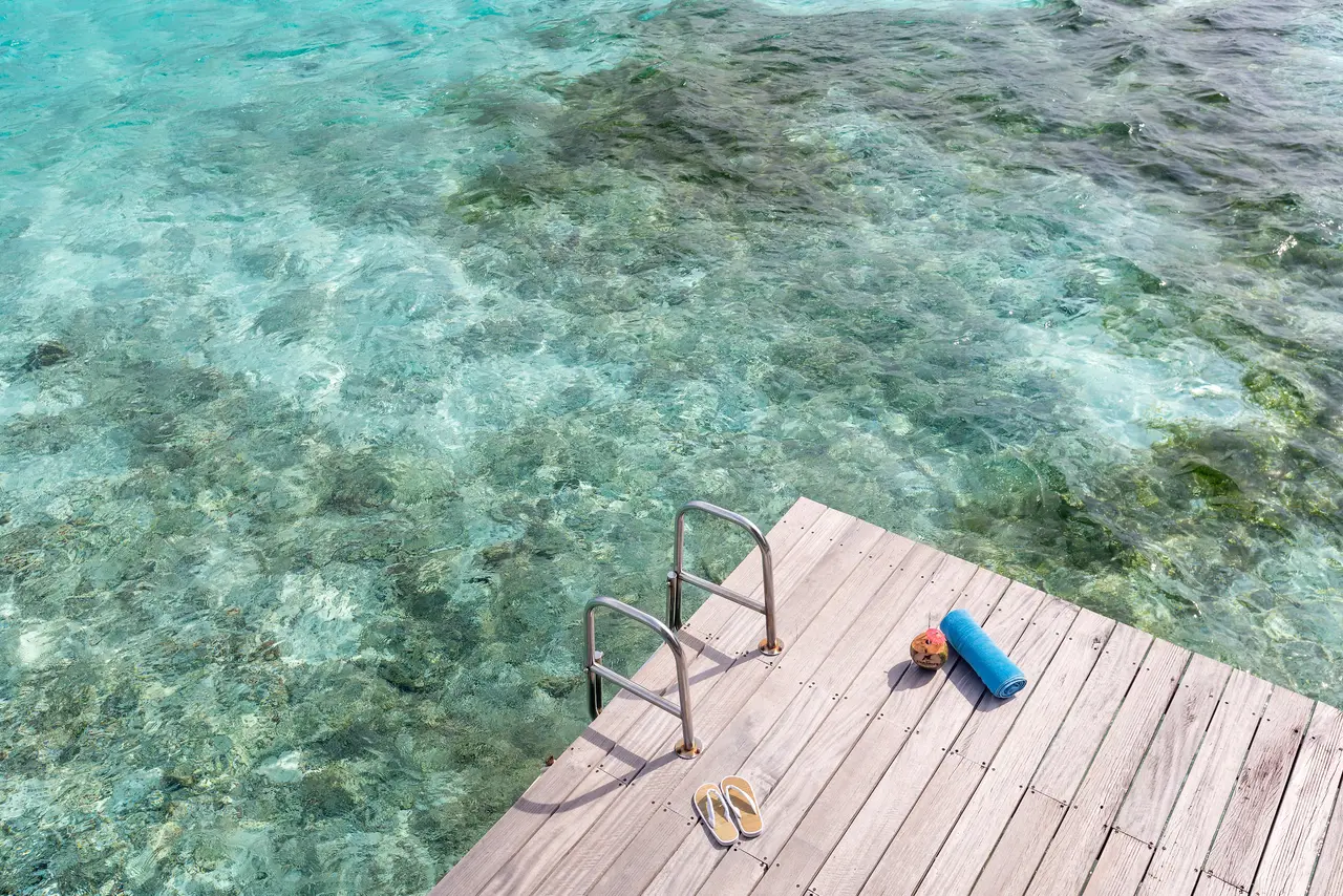 An overwater suite’s platform, with the ladder down into the clear lagoon.
