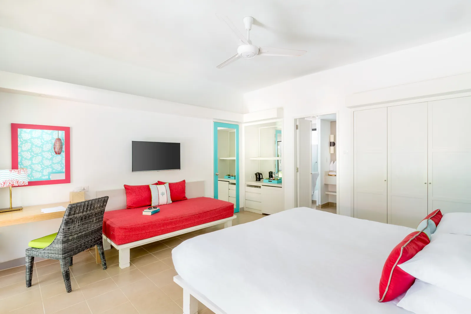 A garden-side Superior room: the bed, the red sofa, the desk and the large white wardrobe.