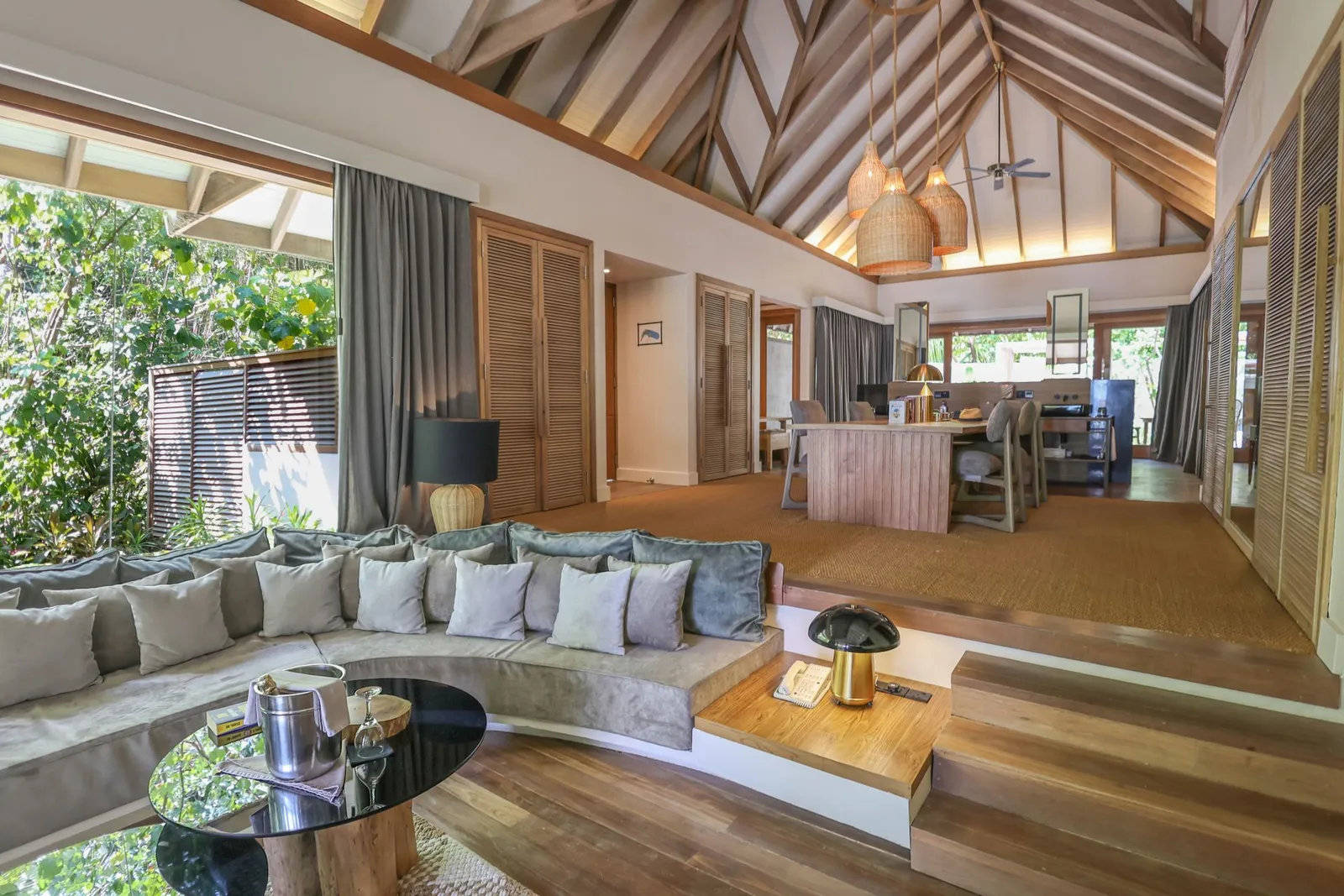 The Grand Premier Beach Villa’s living room: the sunken sofa, the timber-trussed ceiling and the garden beyond the glass.