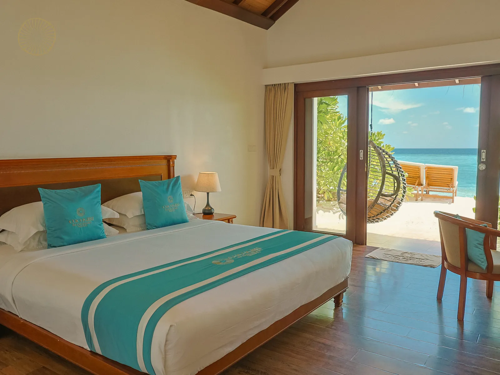 A Beach Villa bedroom: the king bed and, beyond the glass doors, the hanging basket chair and the beach.