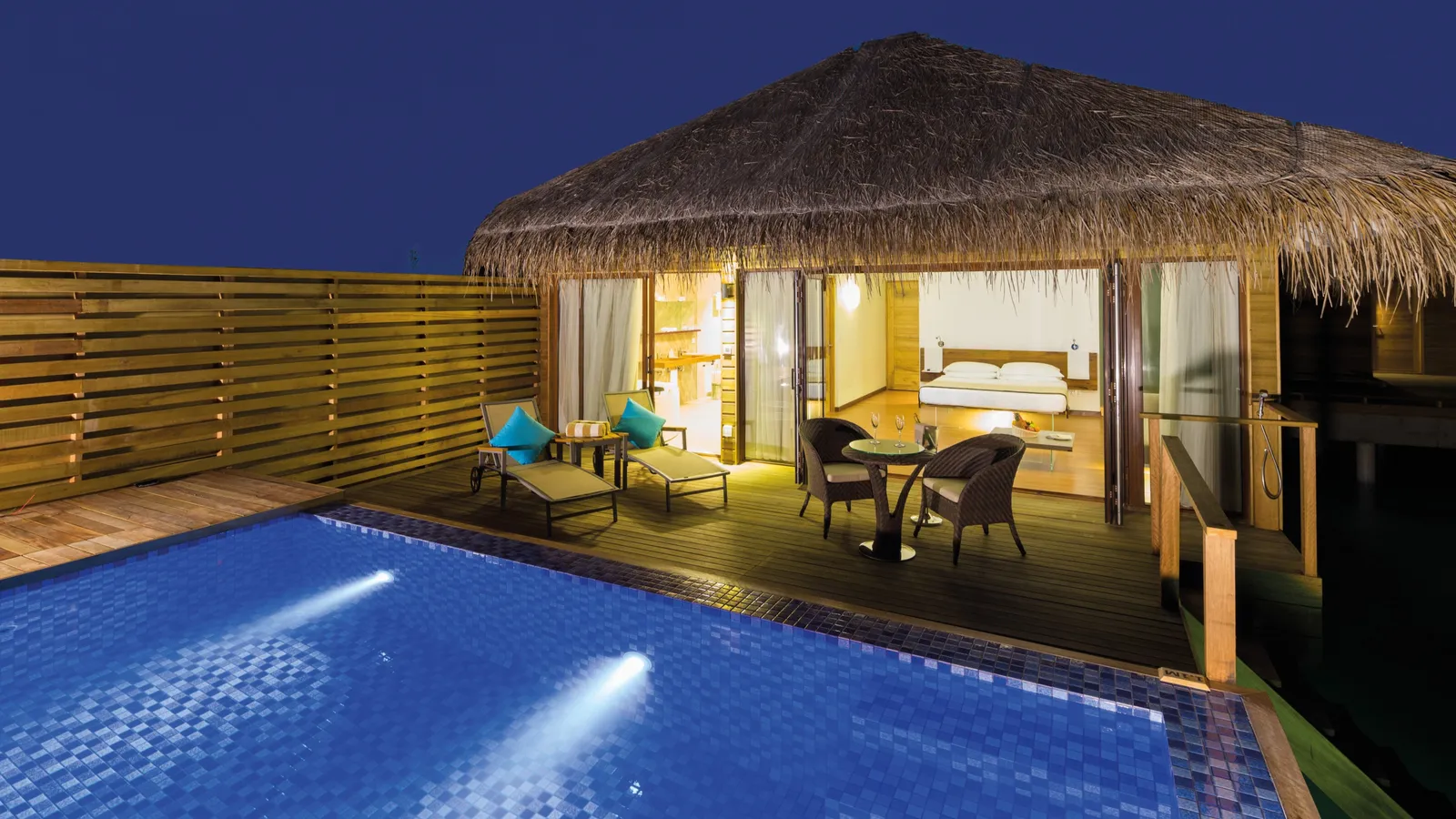 A Lagoon Suite with Pool’s lit pool in the evening, in front of the bedroom