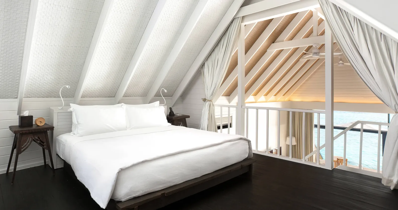 The upstairs bedroom of a Dhoni Loft Water Villa, white under the sloping roof