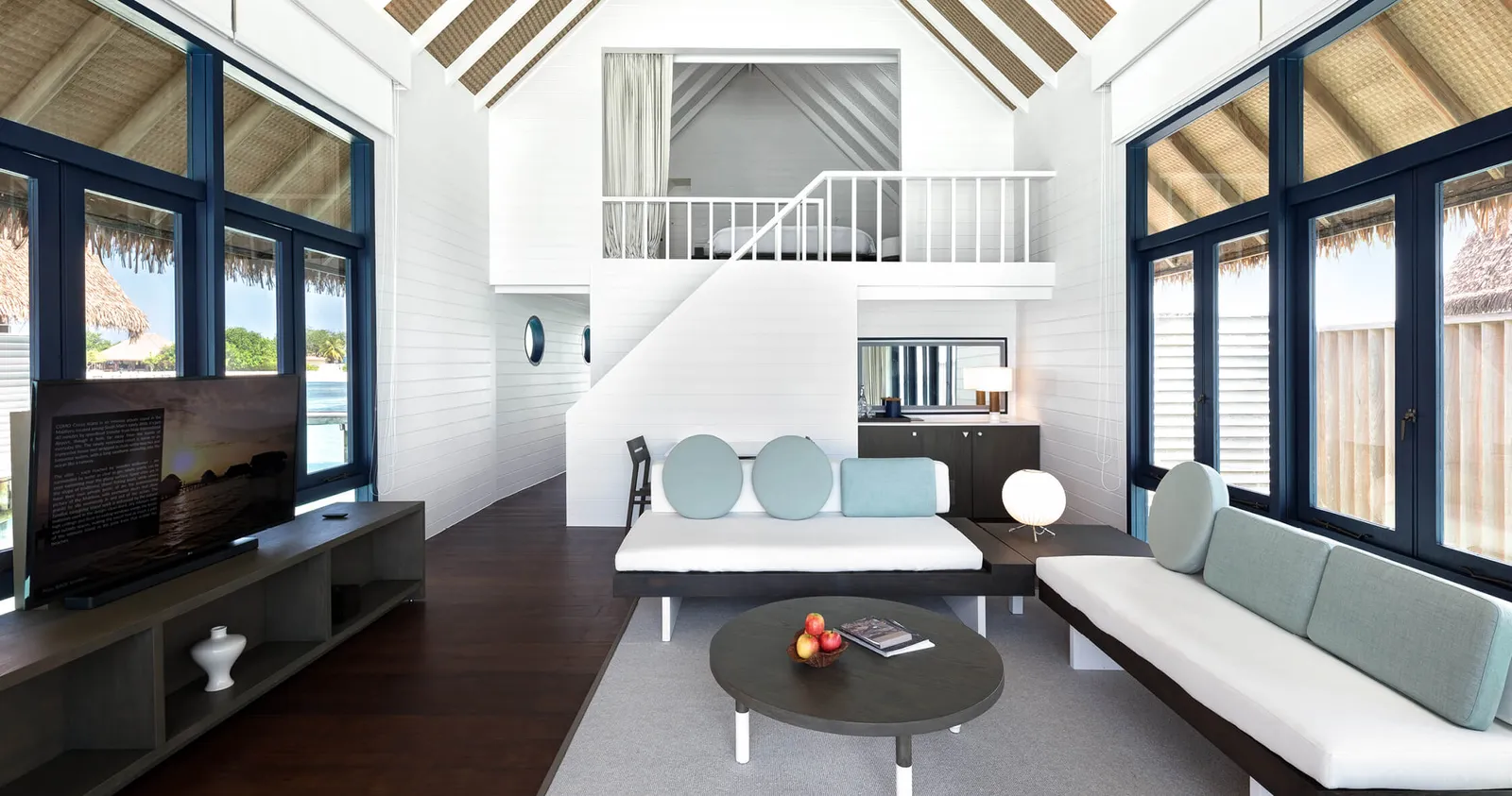 The living room of a Loft Water Villa, with the bedroom on the mezzanine above the sofa