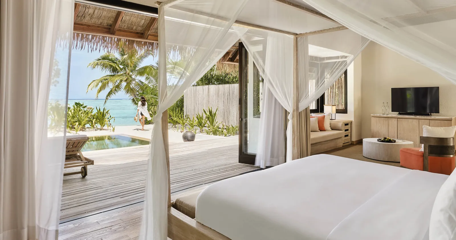 A Beach Suite: the canopy bed, the sitting area and, through the open doors, the terrace with its pool and the garden.