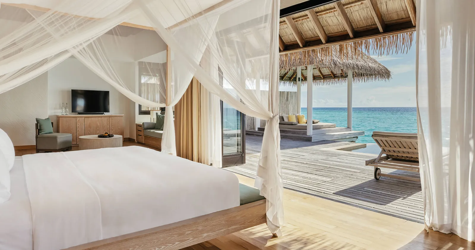 A Water Suite: the bed under its nets and the deck over the water with loungers.