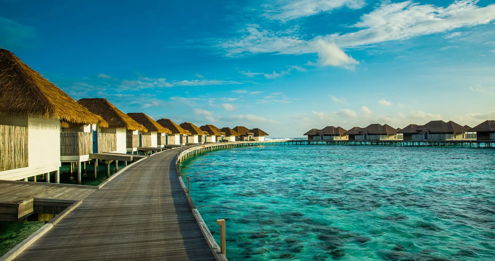 The Water Suites’ jetty curving over the turquoise lagoon to the villas on the water.