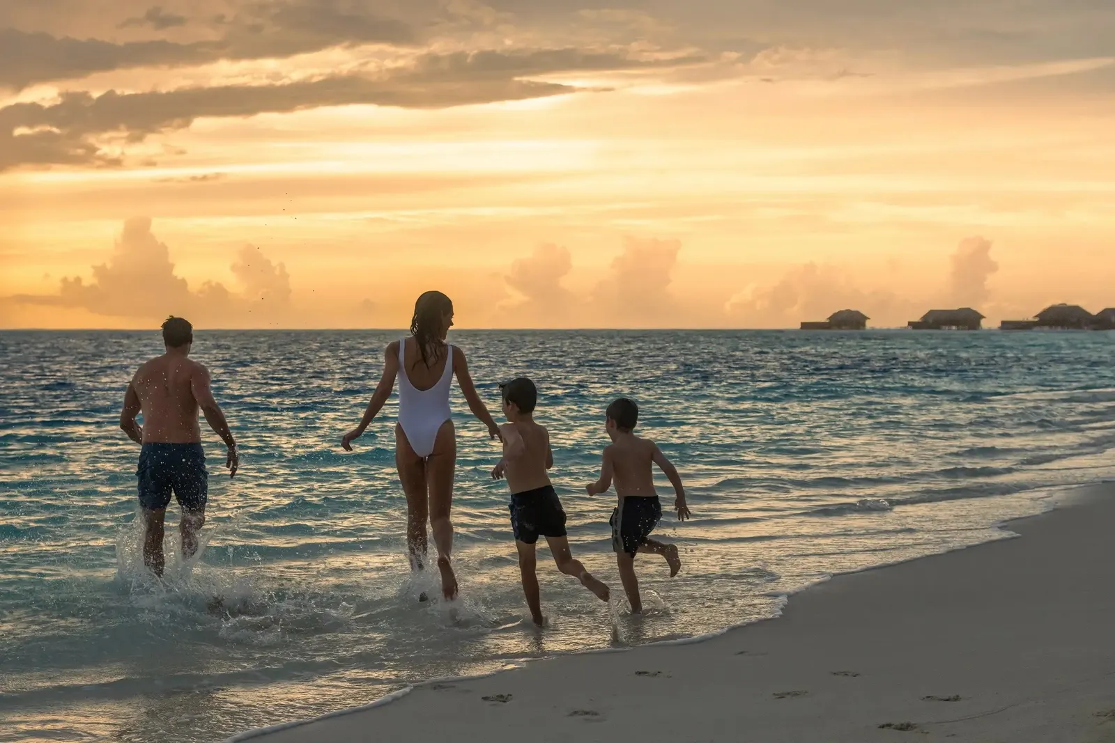 A family running into the sea at sunset