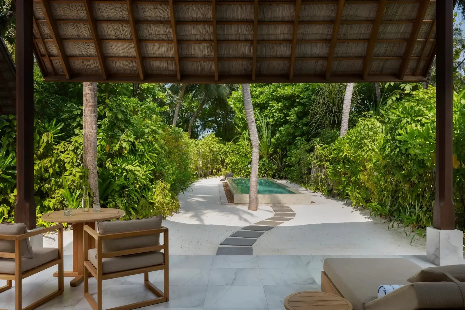 A 2 Bedroom Deluxe Beach Villa with Pool’s outdoor sitting area, the pool in the greenery