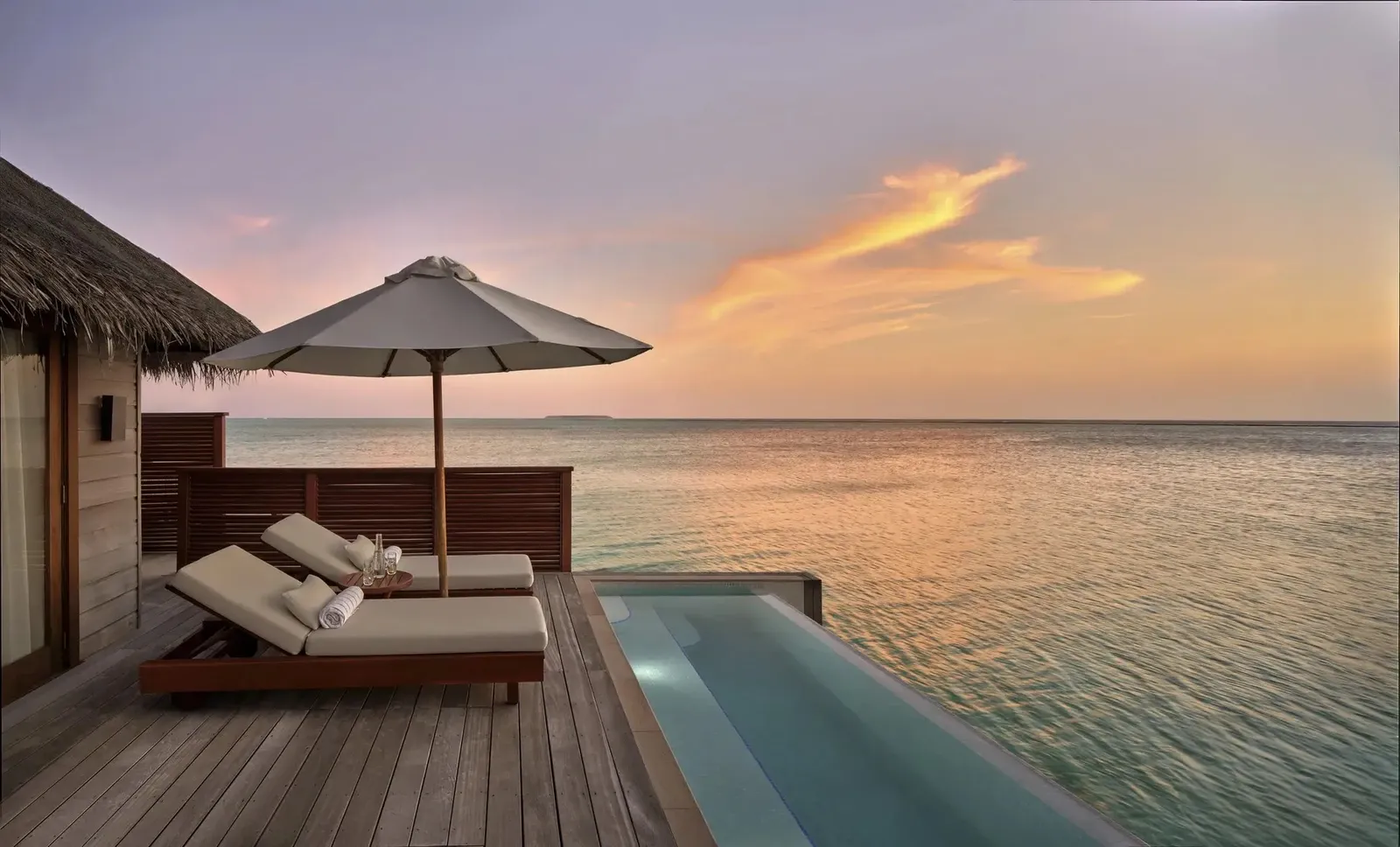 A Deluxe Water Villa with Pool’s deck at sunset