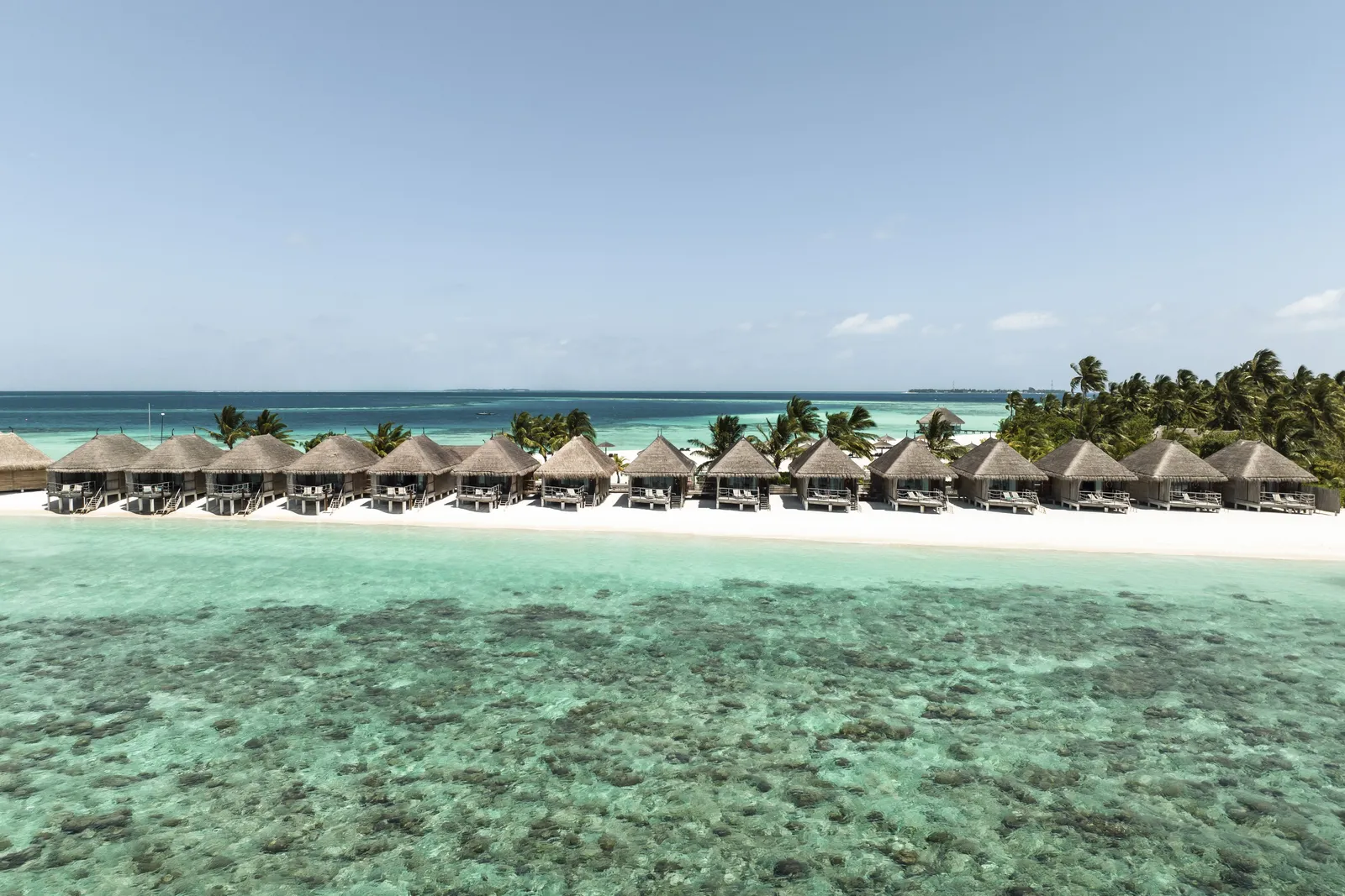 The white beach and the row of water villas over the reef, palms beyond