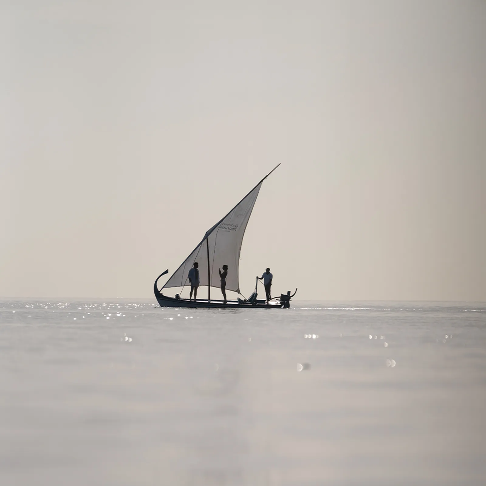 A sailing dhoni on a calm sea, a pale horizon