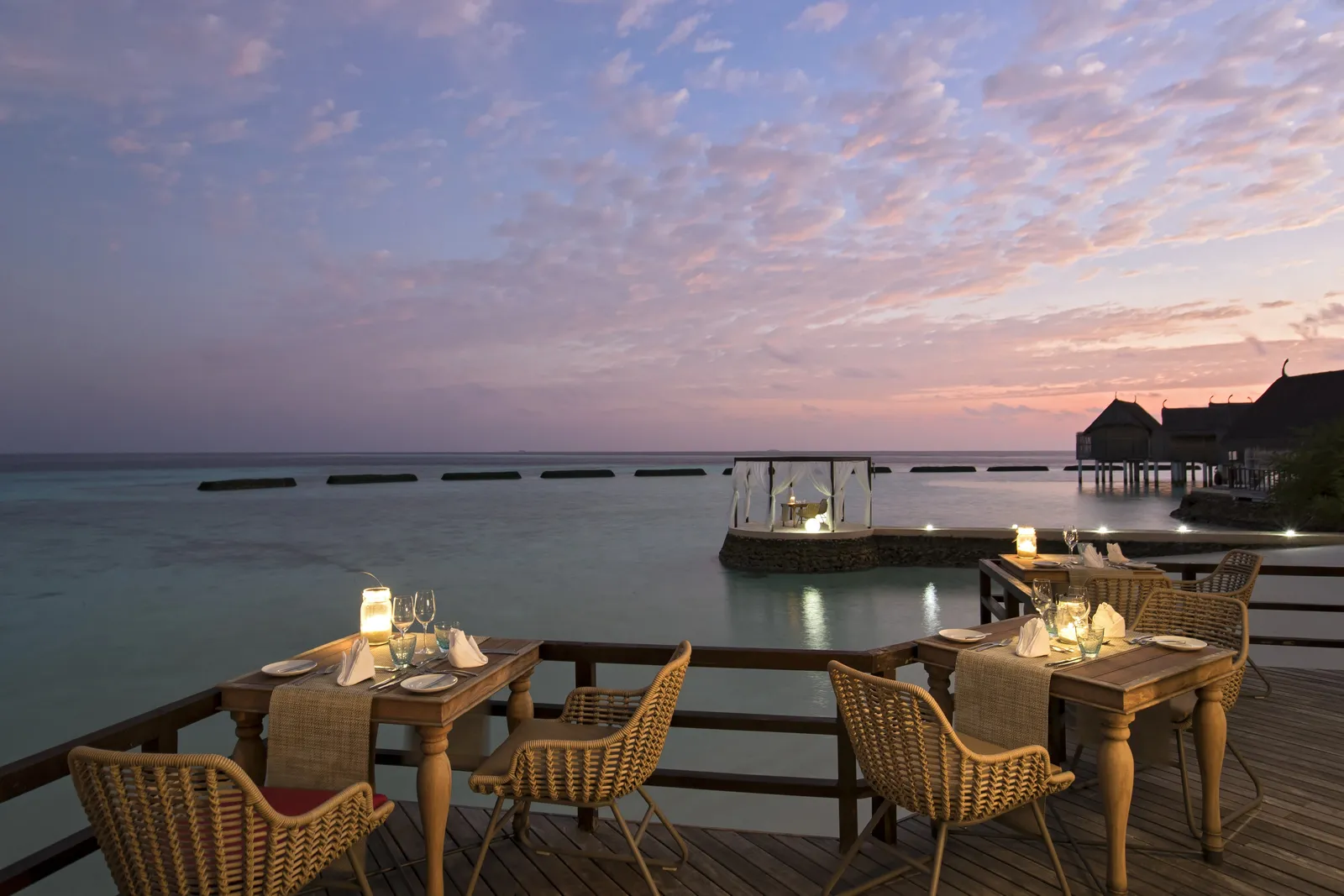 Manta’s deck over the water at dusk, tables laid and lanterns lit.