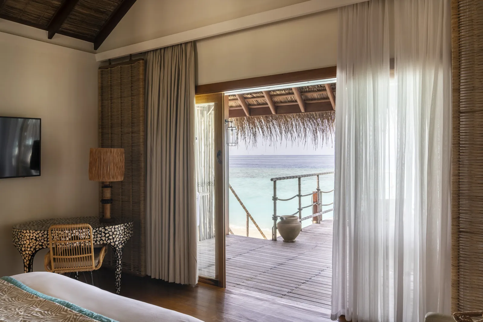 A Sand Villa bedroom: the bed and the open doors to the deck and the lagoon