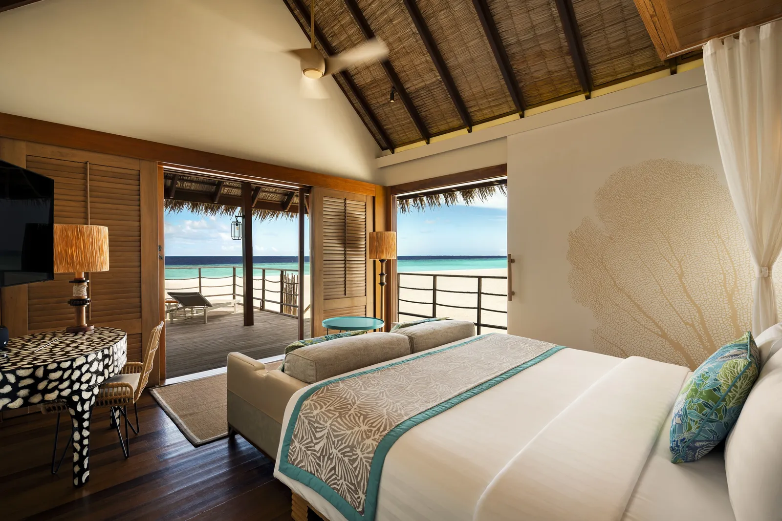A Senior Sand Villa bedroom, its thatched ceiling and the deck over the beach