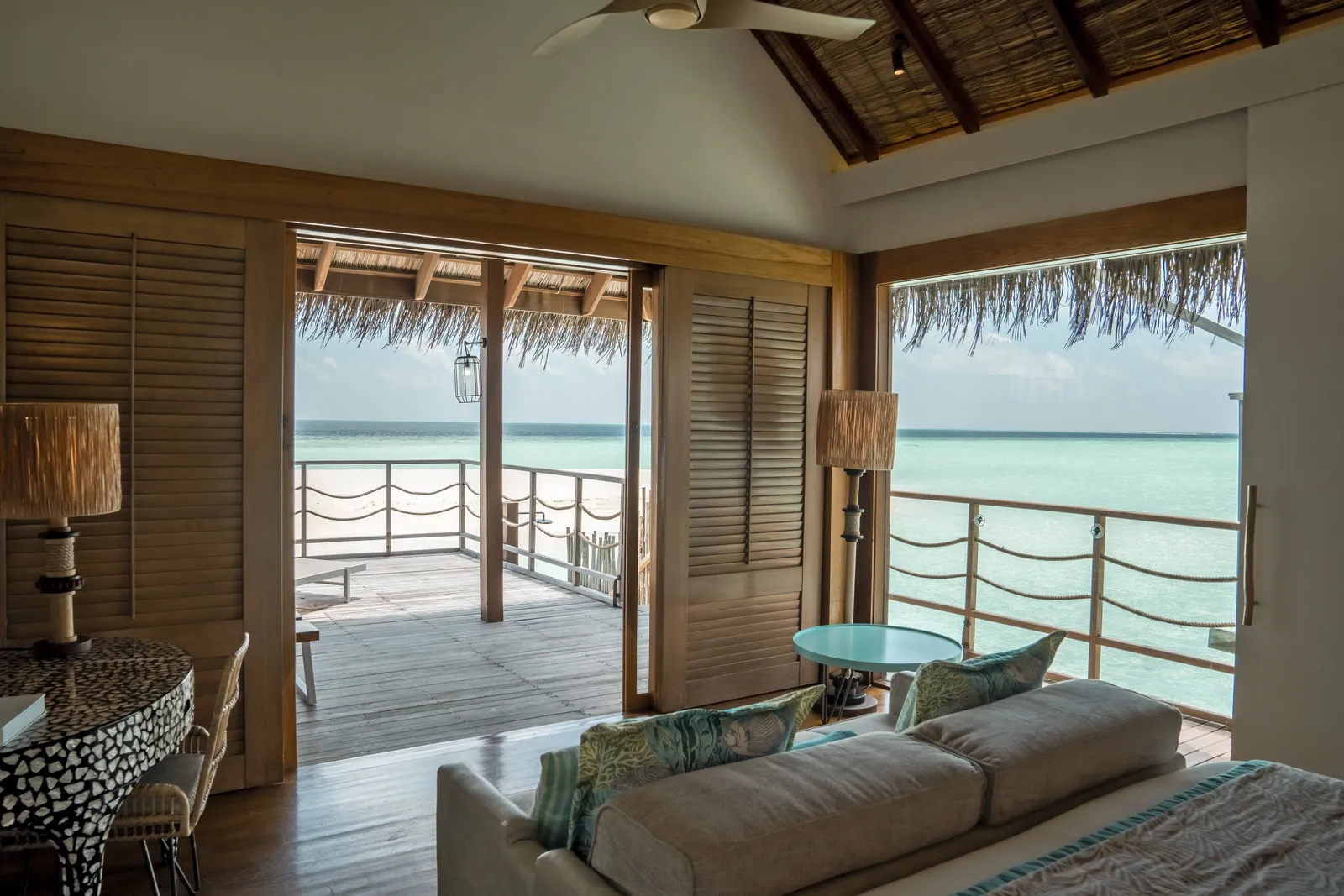 A Senior Water Villa living room, the sofa and the deck open to the sea