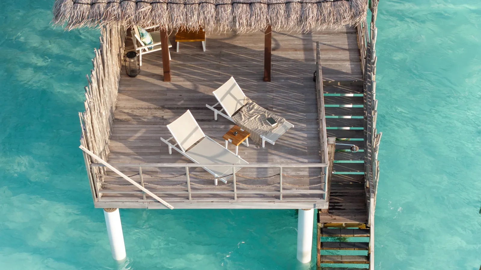 A Water Villa deck from above: 2 loungers and the steps into the lagoon